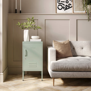 The Camden sage green metal storage locker as a side table next to a sofa