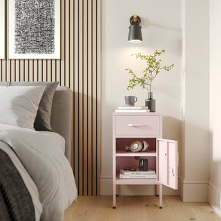 Metal side table locker in light pink with one drawer and one door open showing books, in a room next to a bed